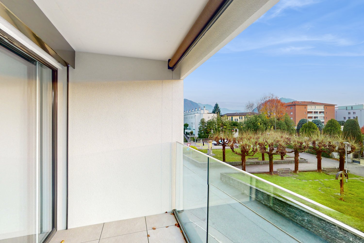Balkon mit Blick ins Grüne und auf Wohngebäude