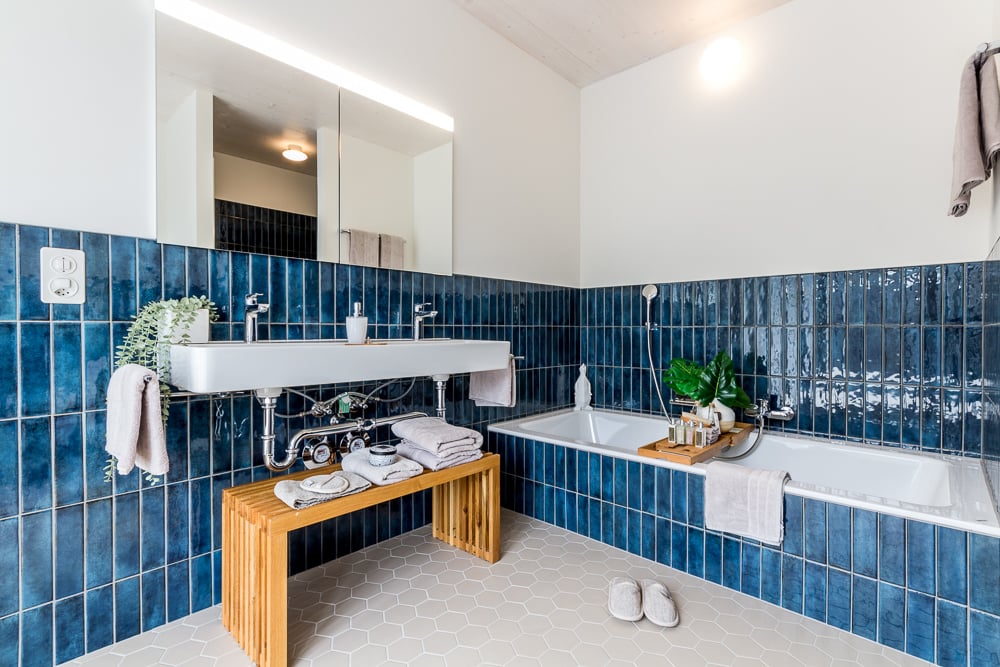 Modernes Badezimmer mit blau gefliesten Wänden und Badewanne