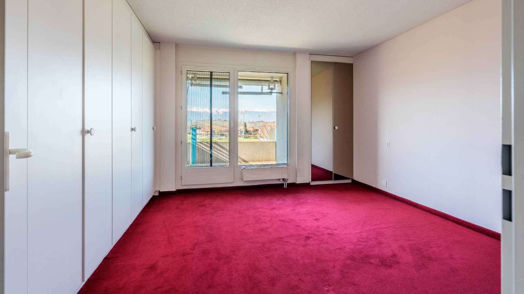 Helles Schlafzimmer mit Einbauschränken und Balkonblick