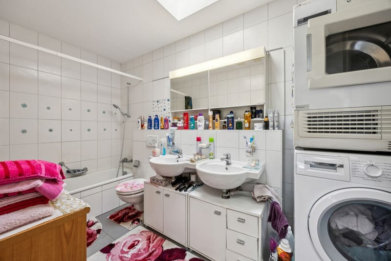Helles Badezimmer mit Doppelwaschtisch und Waschmaschine