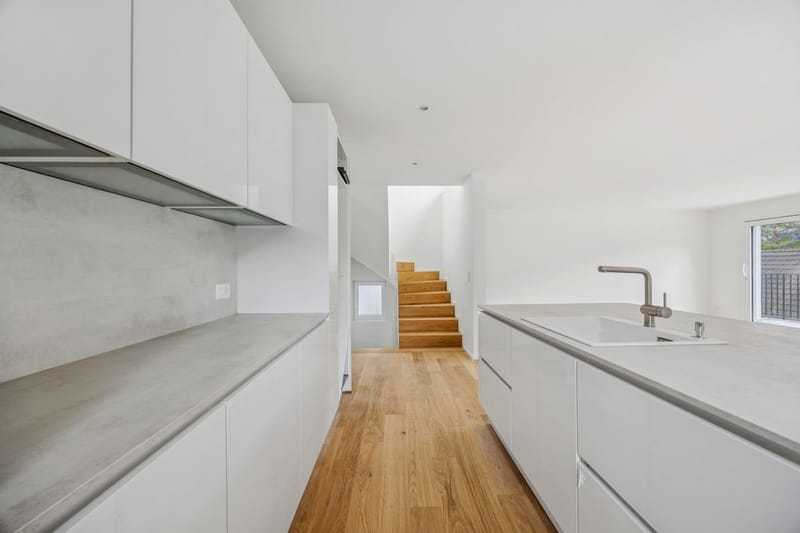 Moderne helle Küche mit Treppe im Hintergrund