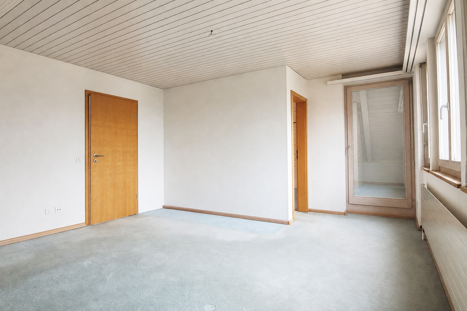 Leerer Dachgeschossraum mit Balkonzugang