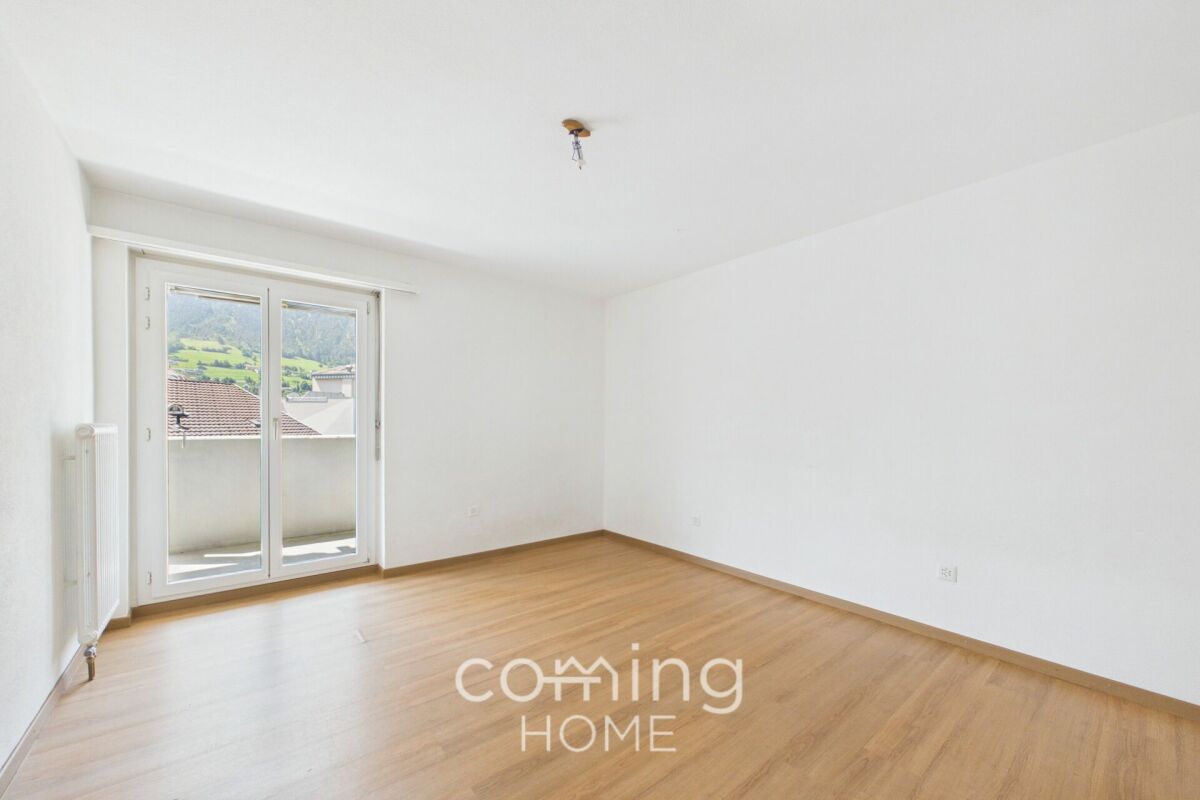 Helles, leeres Zimmer mit Balkon und Ausblick ins Grüne