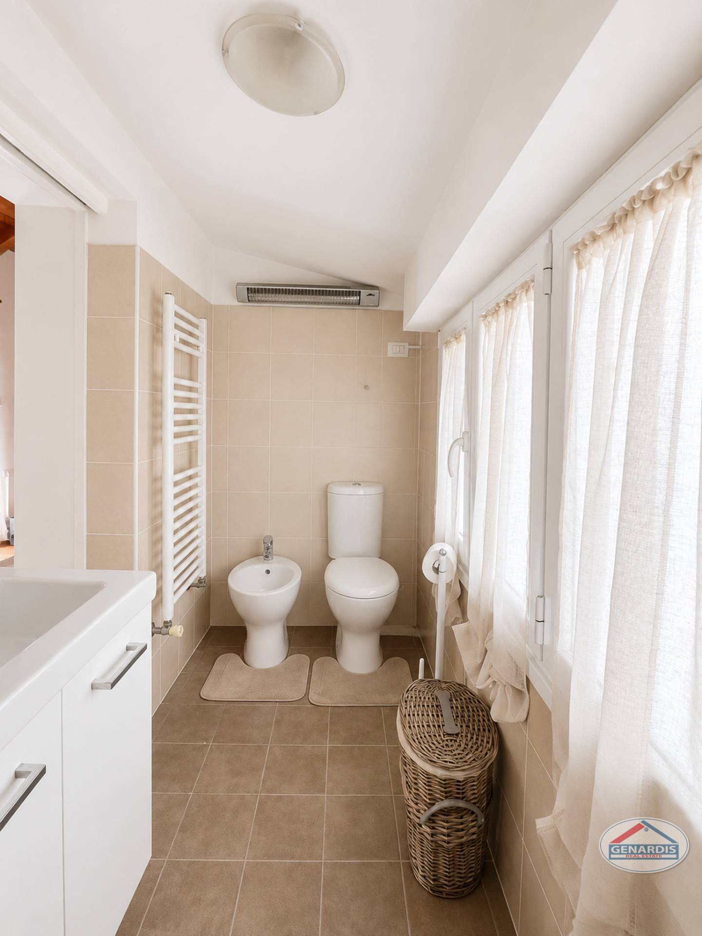 Helles kleines Gäste-WC mit beige gefliesten Wänden und Fensterfront