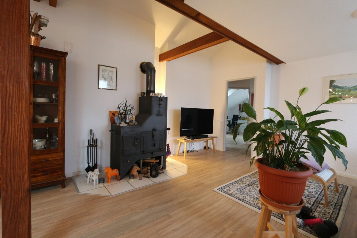 Wohnzimmer mit Holzofen und sichtbaren Holzbalken