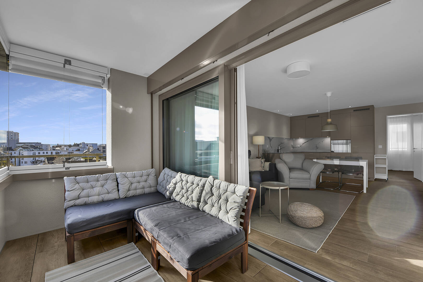 Überdachter Balkon mit Wohnbereich und Blick in den offenen Wohnraum