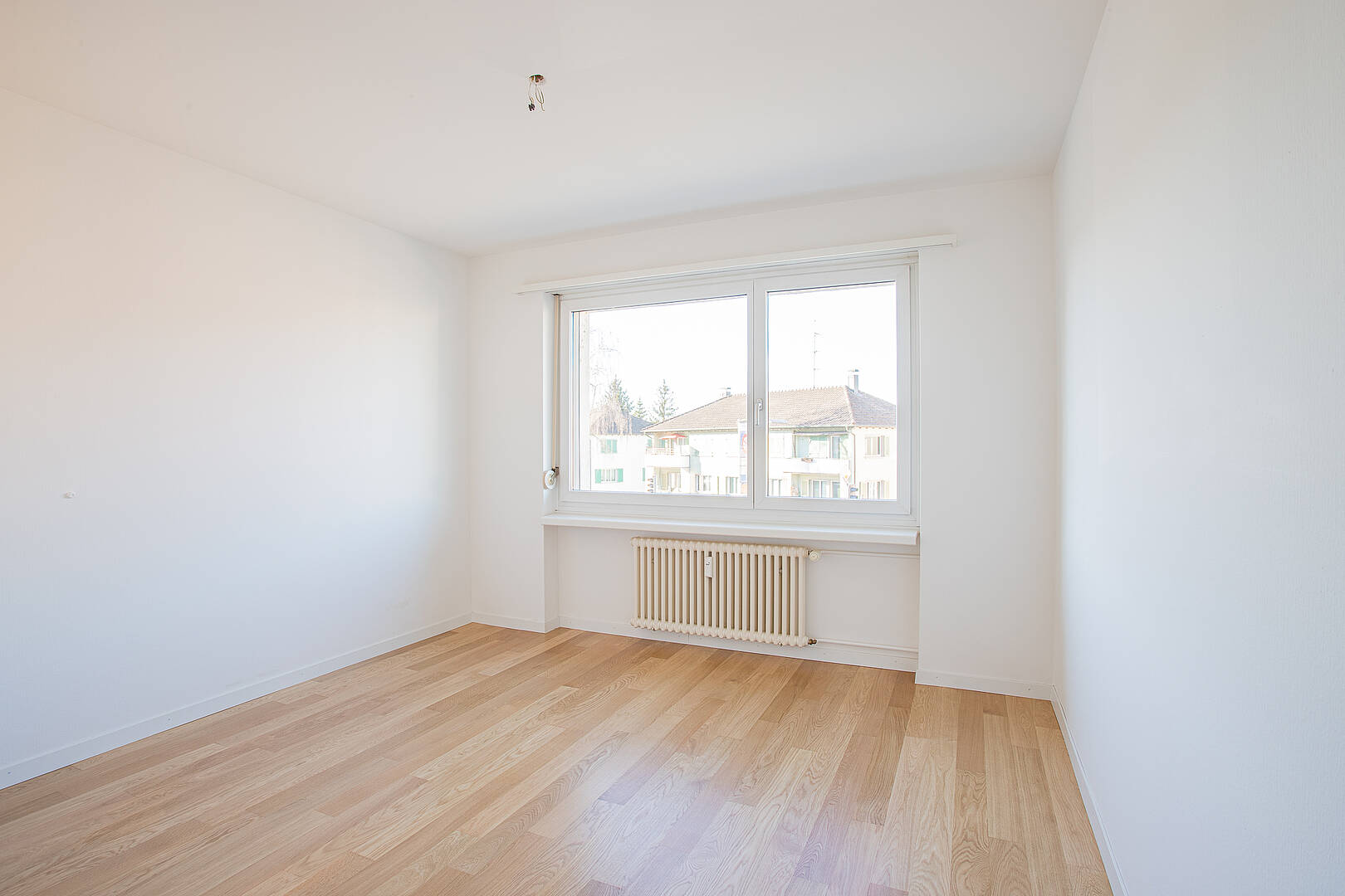 Leeres, helles Zimmer mit Parkett und Fenster