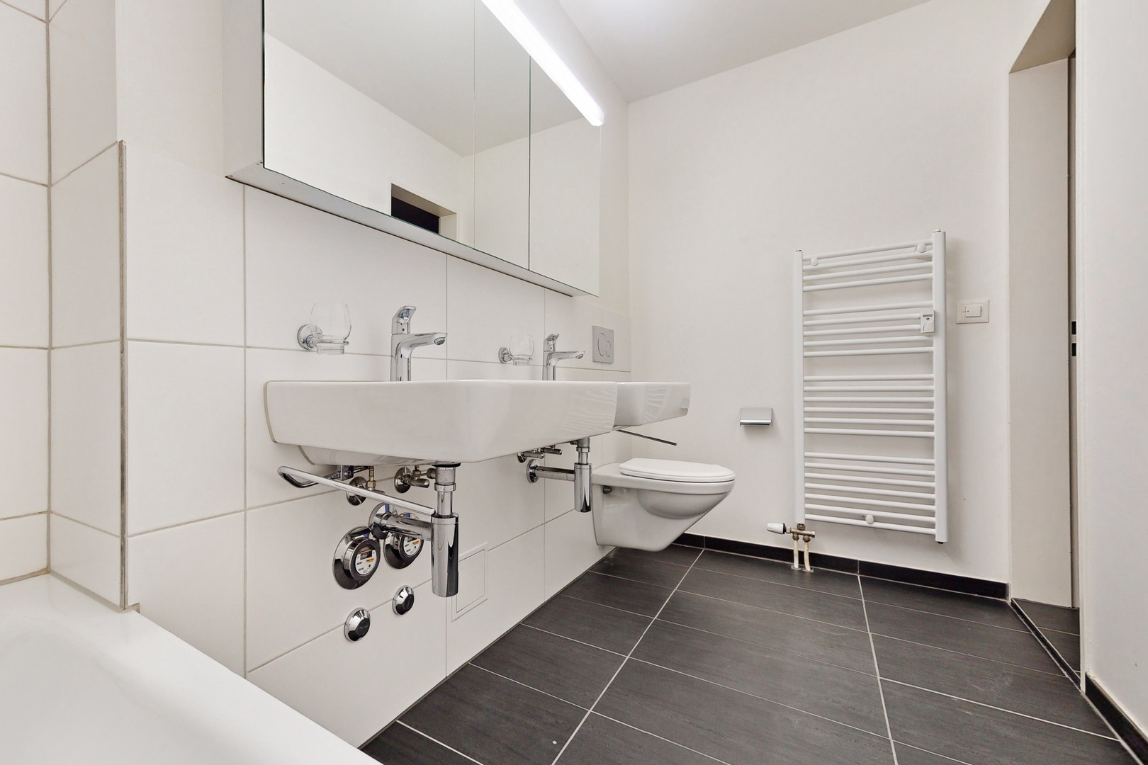 Modernes kleines Badezimmer mit wandhängendem WC und Doppelwaschbecken