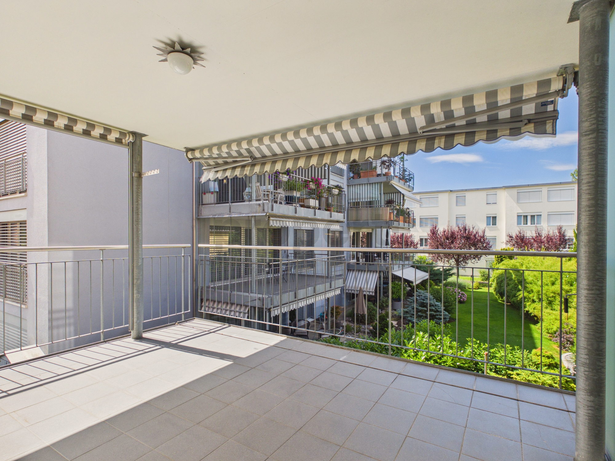 Überdachter Balkon mit Blick auf Innenhof und Nachbargebäude