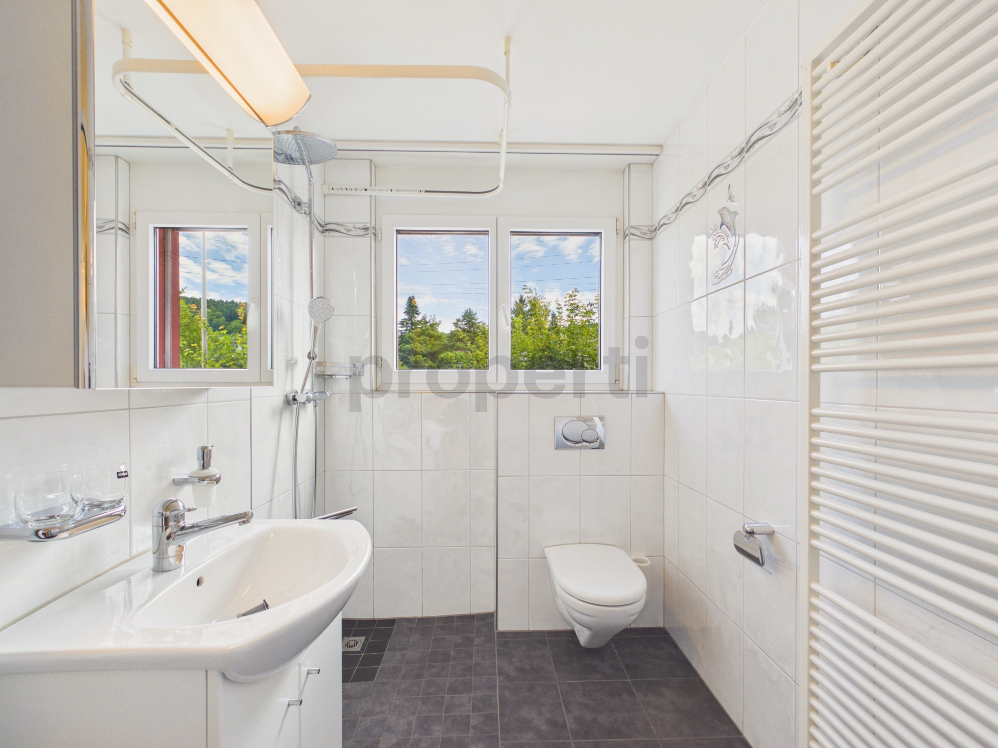 Helles Badezimmer mit Fensterfront und Wand-WC
