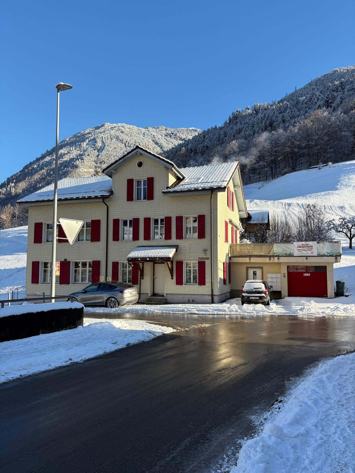 Alpenhaus mit roter Fensterläden und verschneiter Umgebung