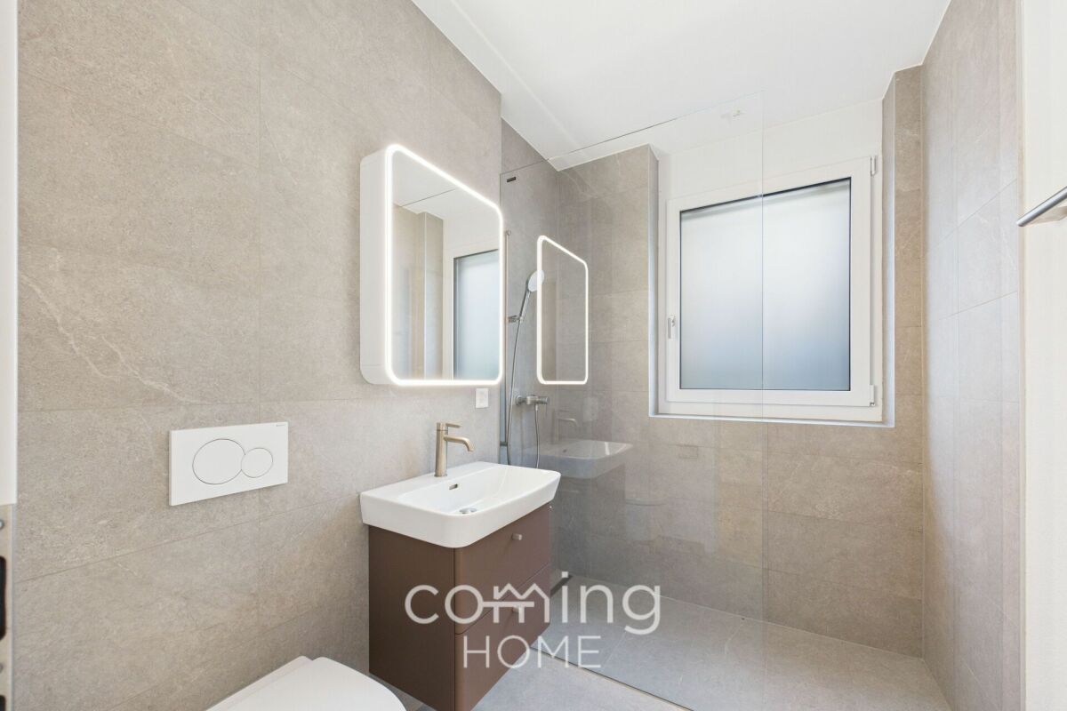 Modernes Badezimmer mit beleuchtetem Spiegel und Walk-in-Dusche