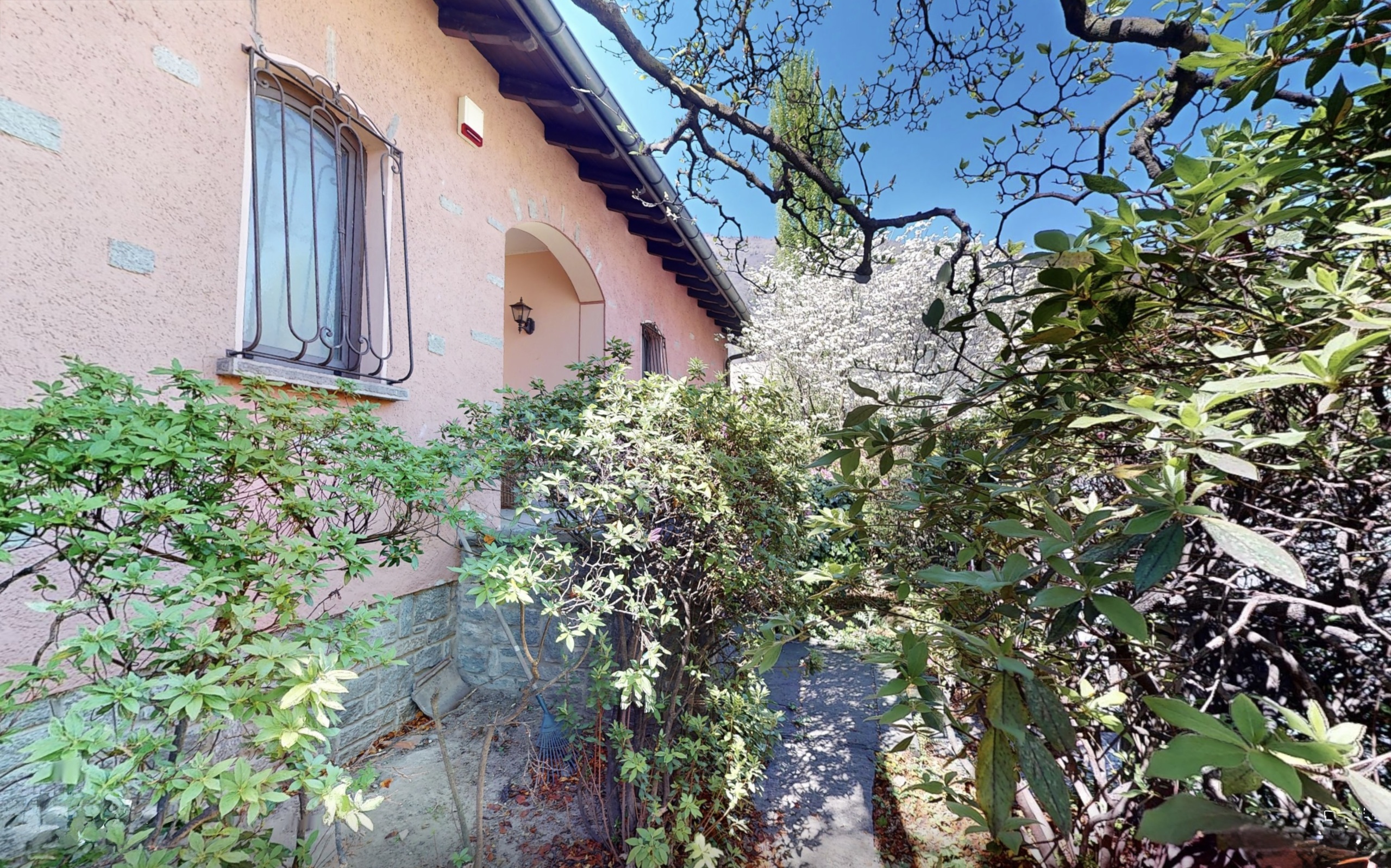 Mediterrane Hausfassade mit üppigem Garten