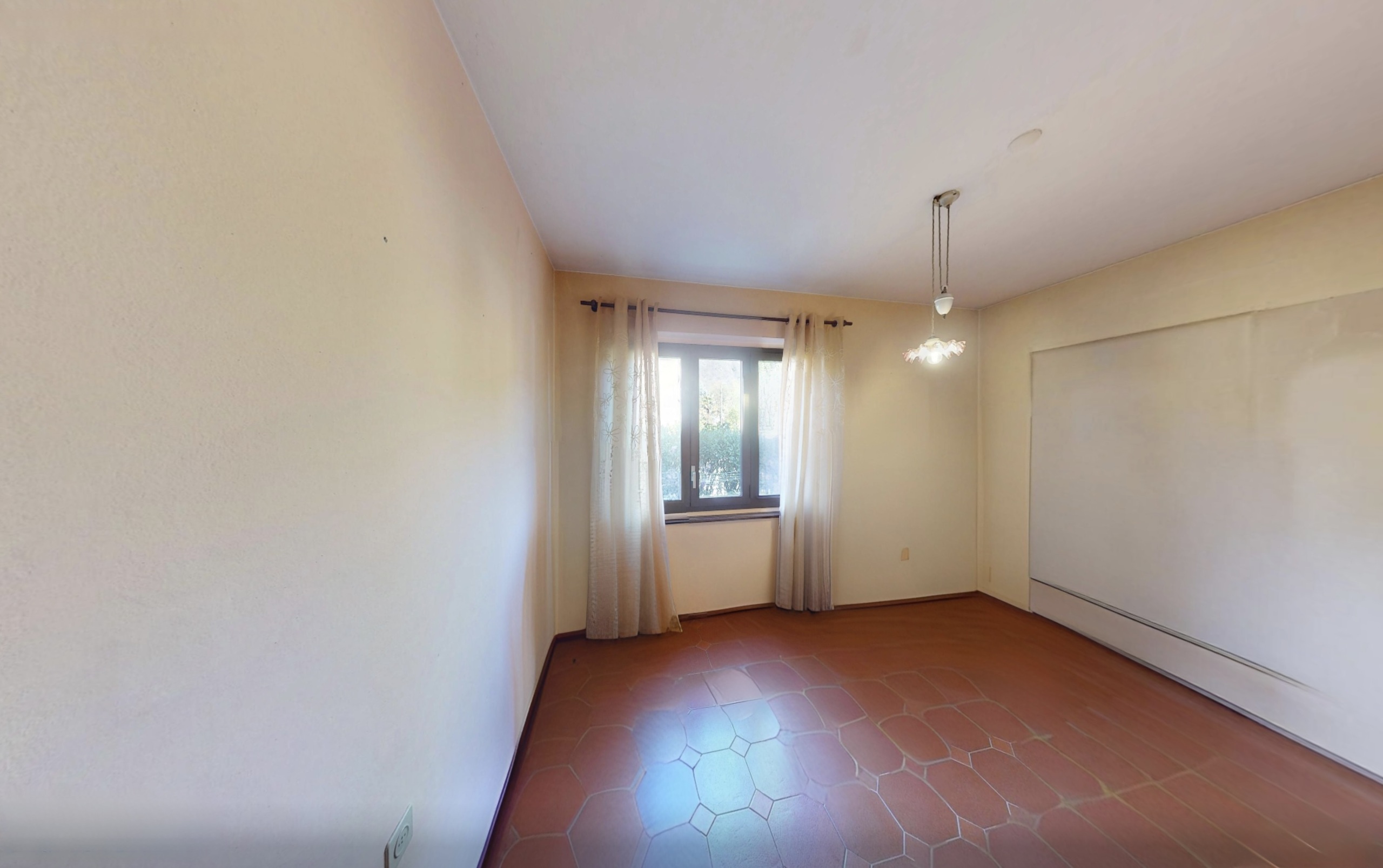 Leerer Wohnraum mit Fliesenboden und Fenster
