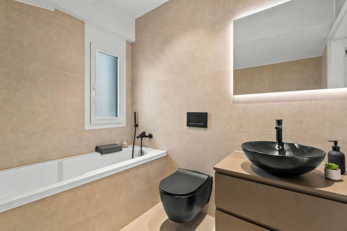 Modernes Badezimmer mit Wanne, schwarzer Aufsatzwaschbecken-Kombination und Spiegel