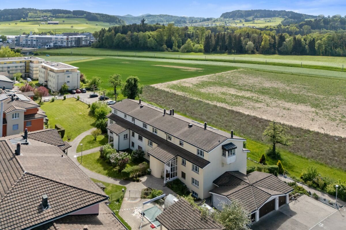 Luftaufnahme eines Wohngebiets am Stadtrand mit Blick auf Felder und Hügel