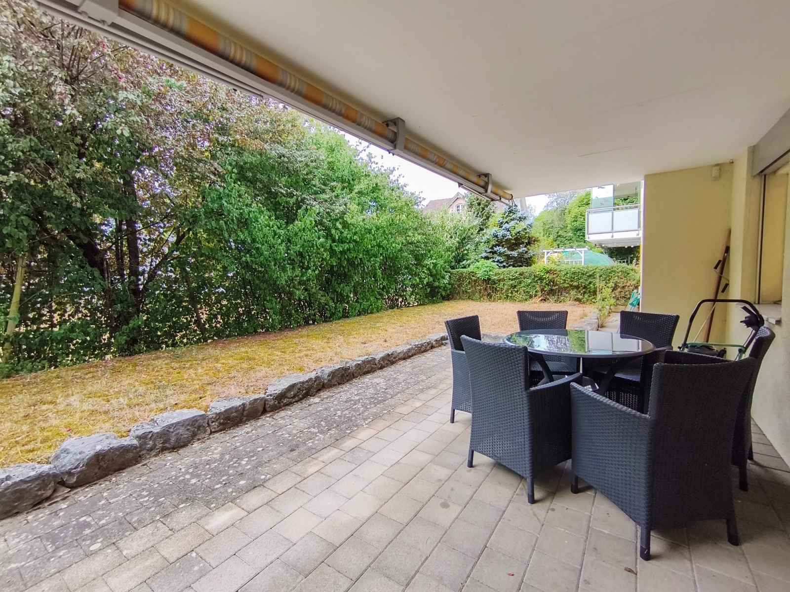 Überdachte Terrasse mit Sitzgruppe und Gartenblick