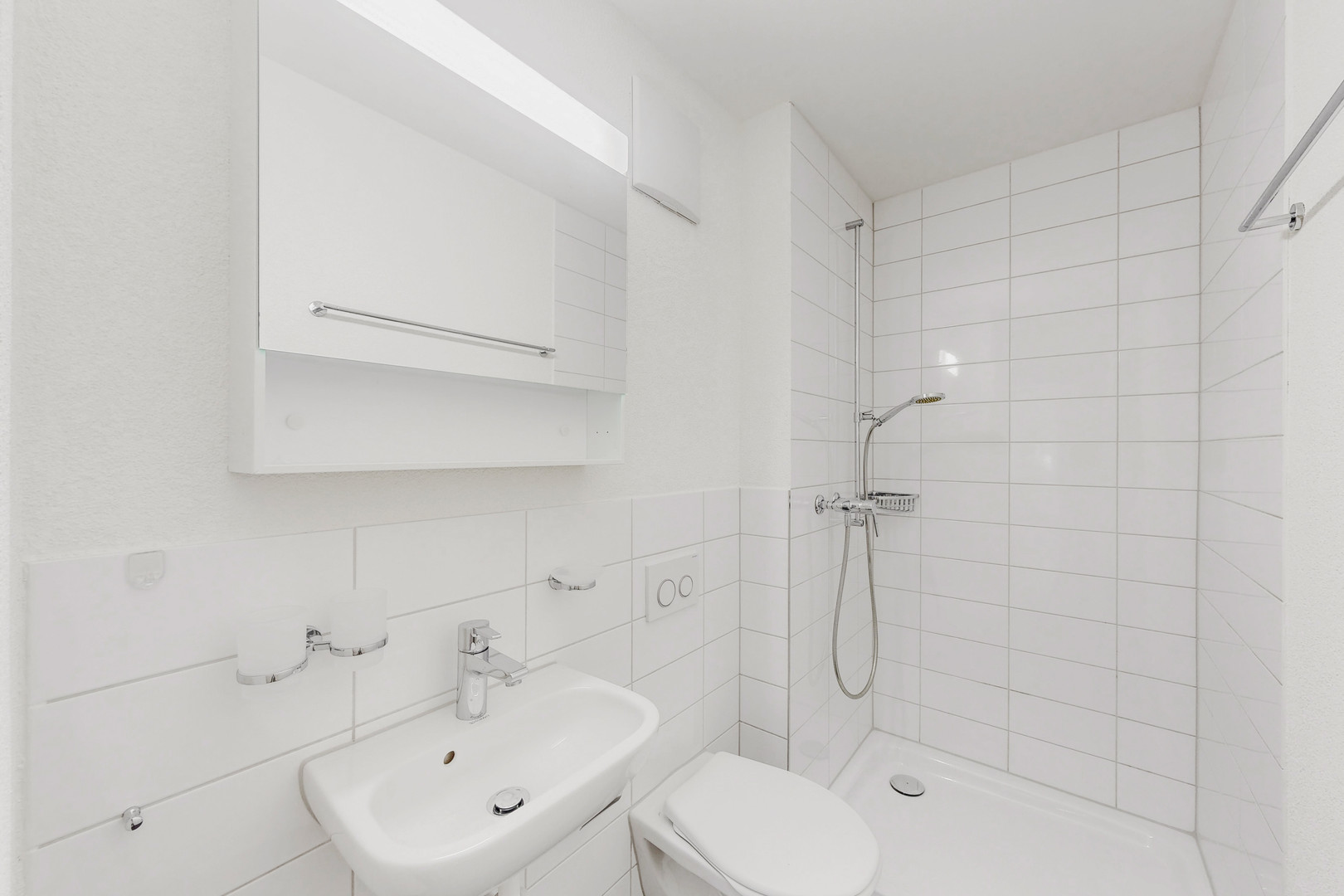 Kleines weißes Badezimmer mit Dusche und Waschtisch