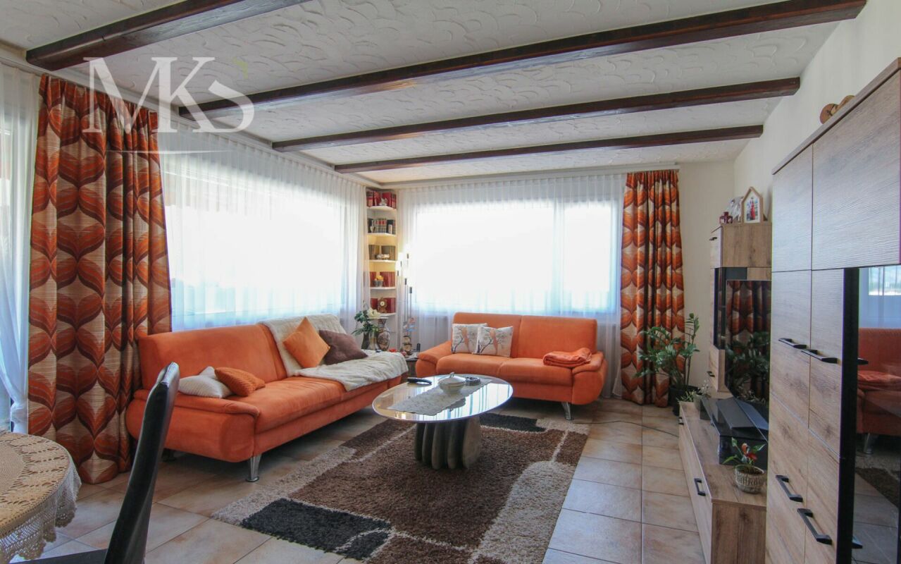 Wohnzimmer mit orangefarbenen Polstermöbeln und Holzdecke