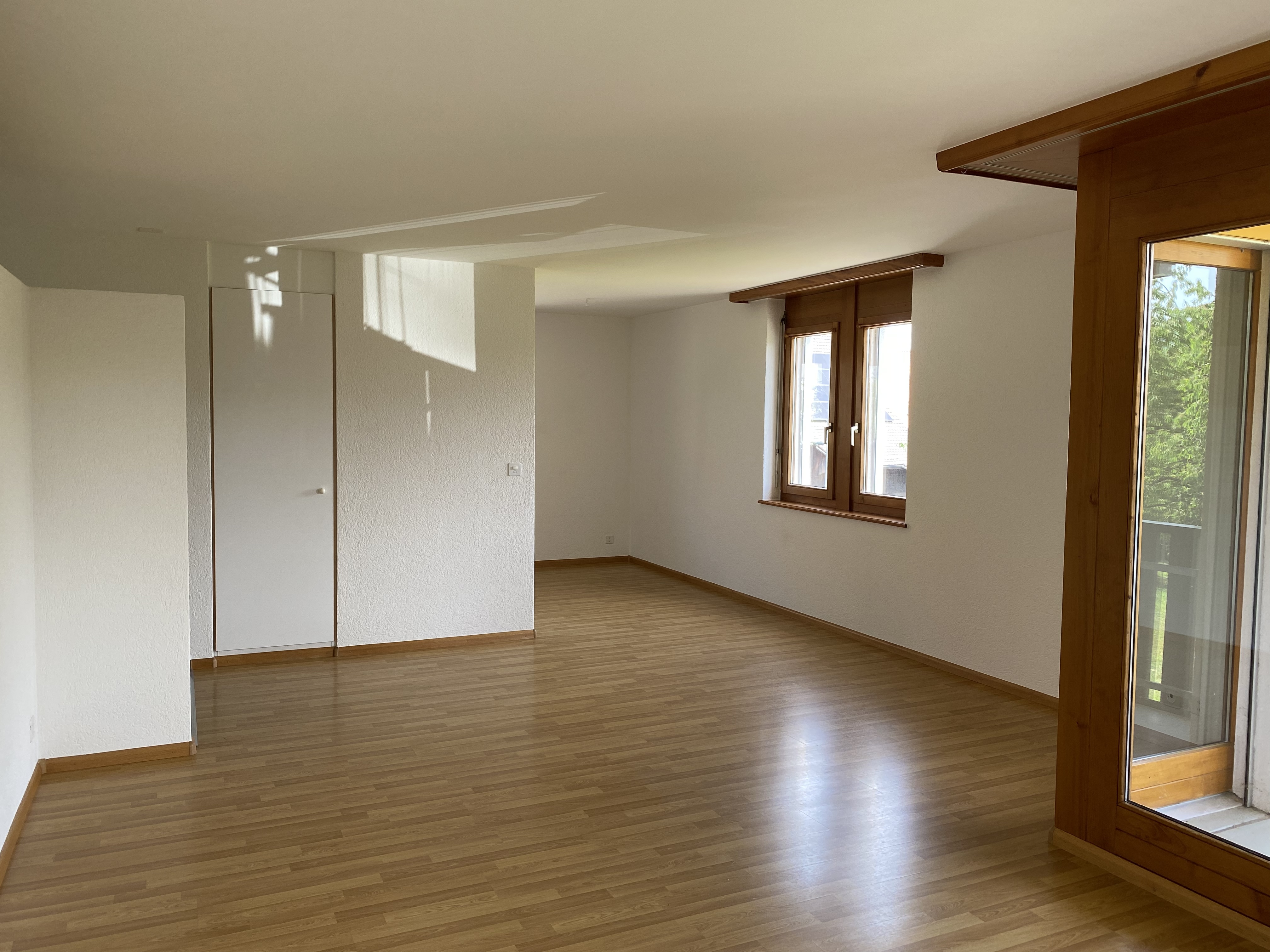 Heller leerer Wohnraum mit Holzfenstern