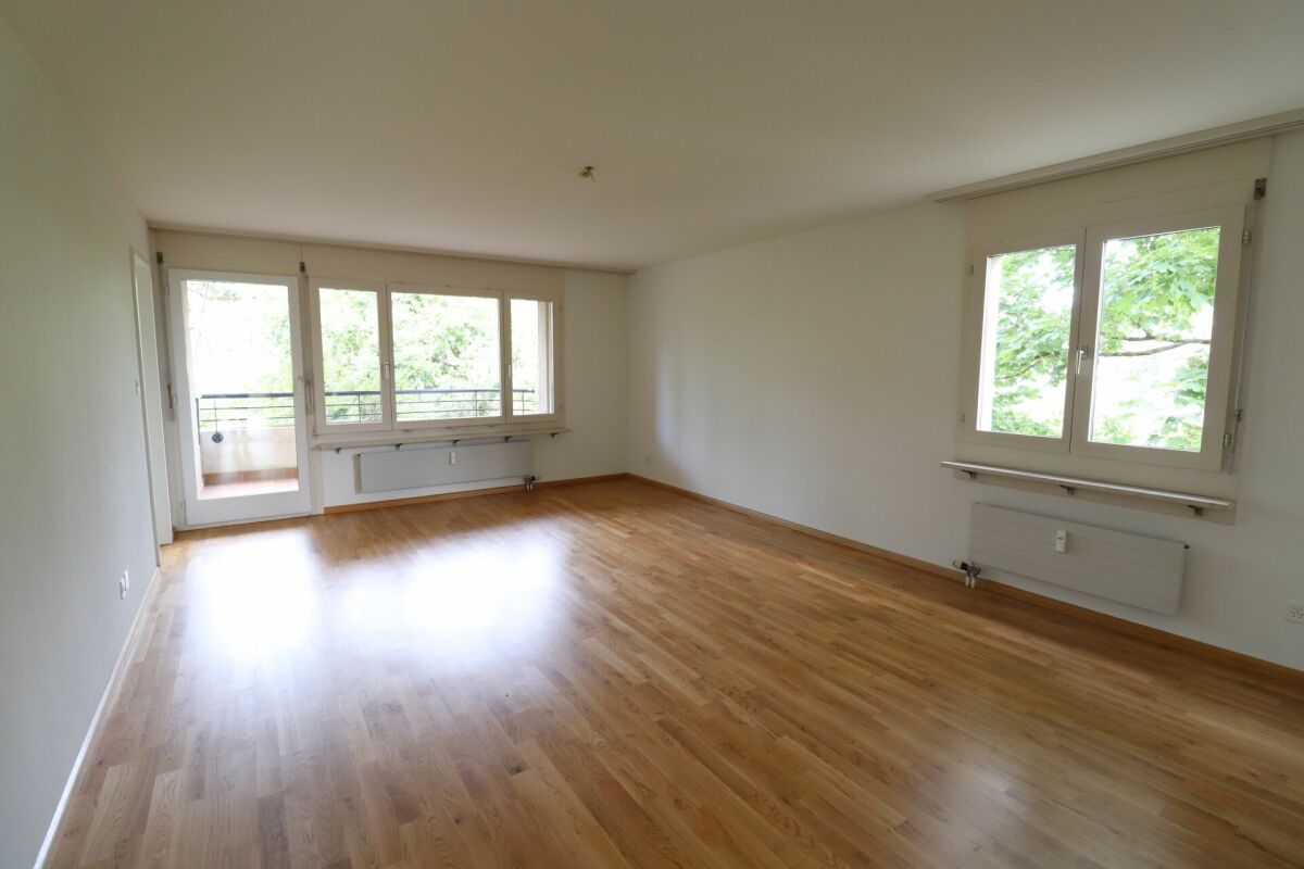 Heller leerer Wohnraum mit Holzfußboden und Fenstern