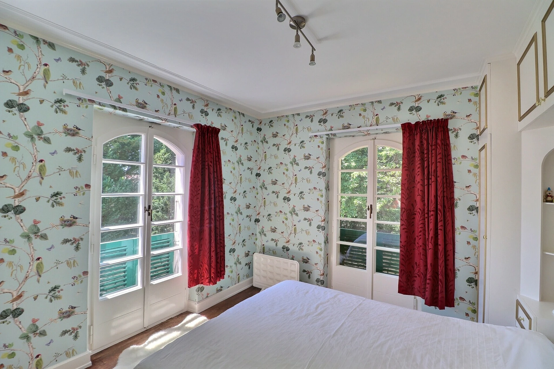 Schlafzimmer mit floraler Tapete und französischen Türen