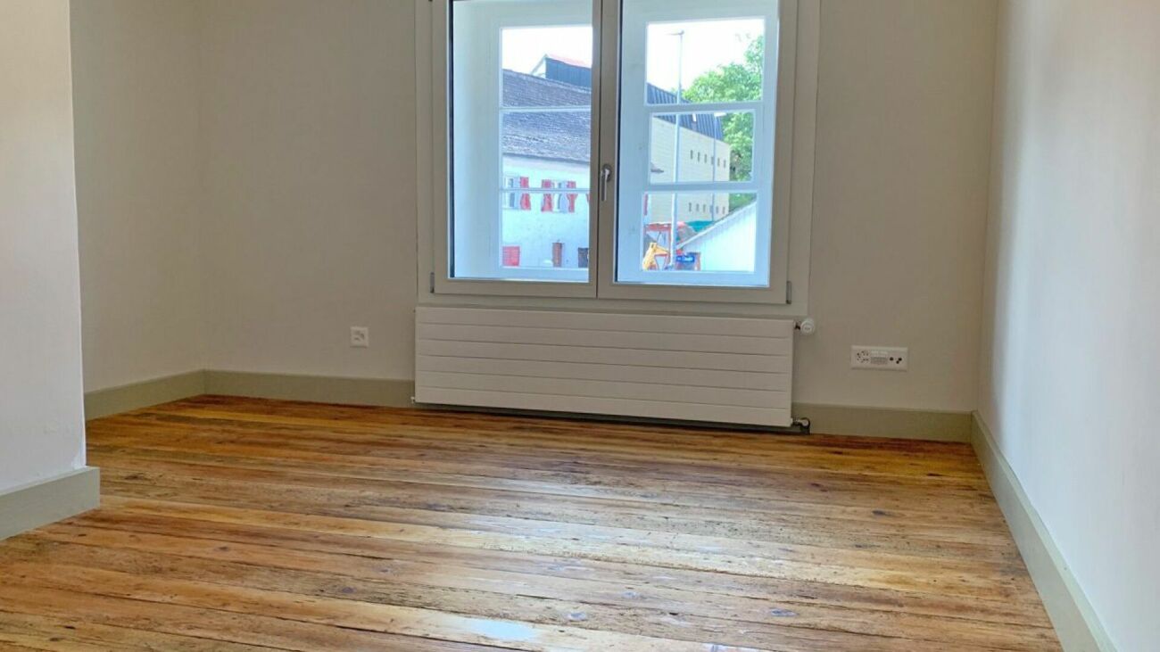 Leerer heller Raum mit Holzfußboden und Fenster
