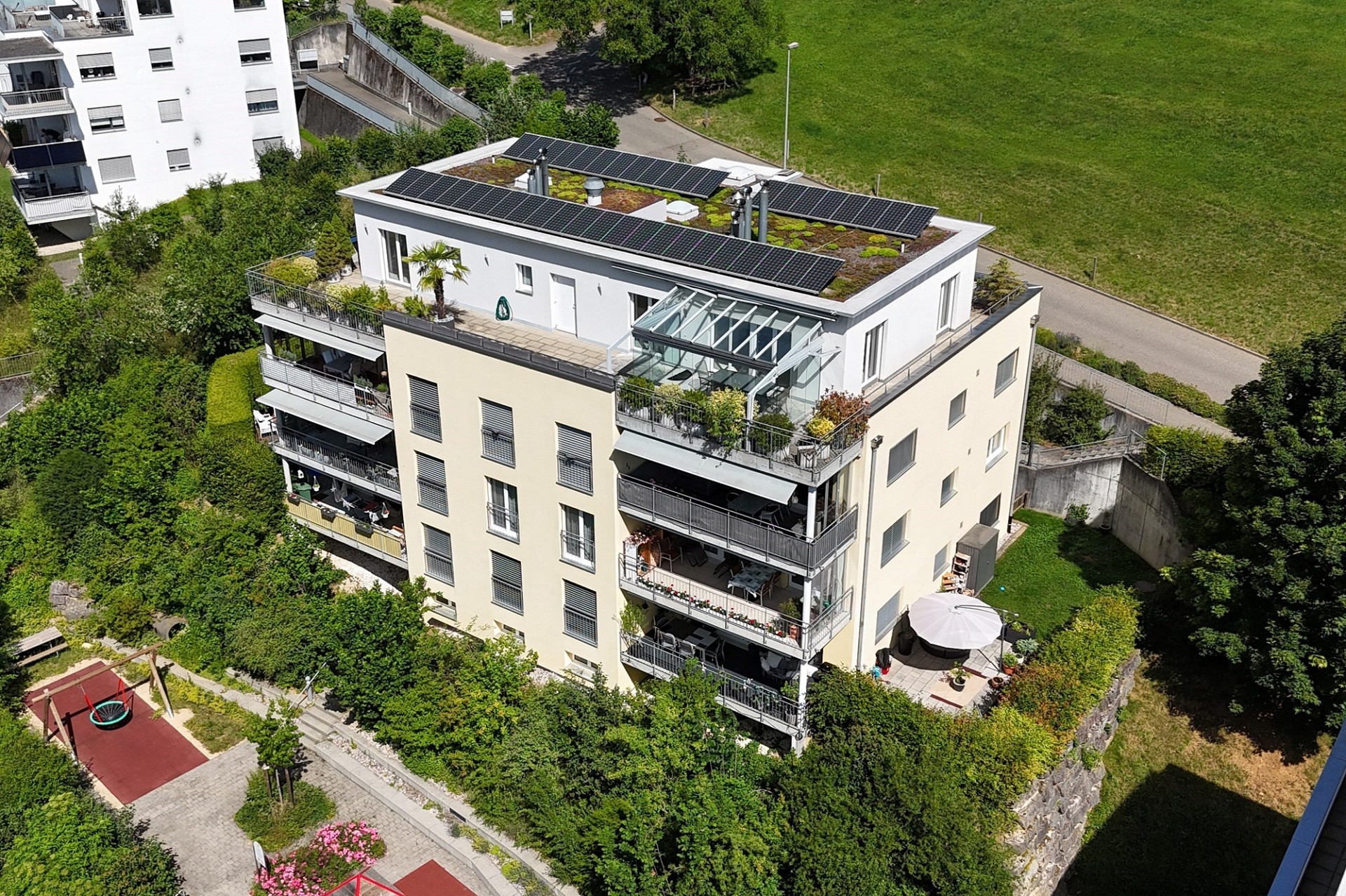 Aerialansicht eines modernen Mehrfamilienhauses mit Dachbegrünung und Solaranlage