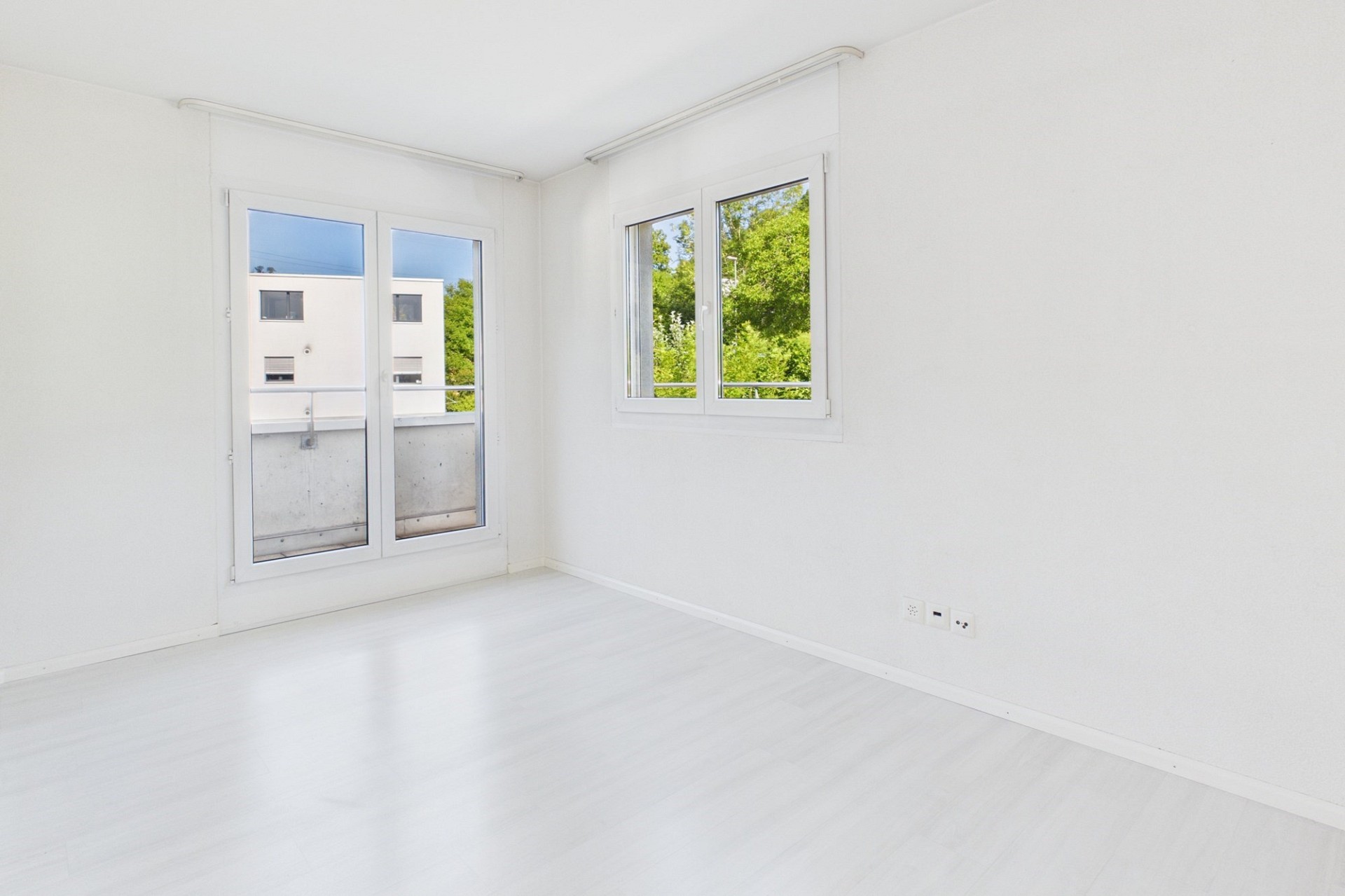 Heller leerer Wohnraum mit Balkonfenstern