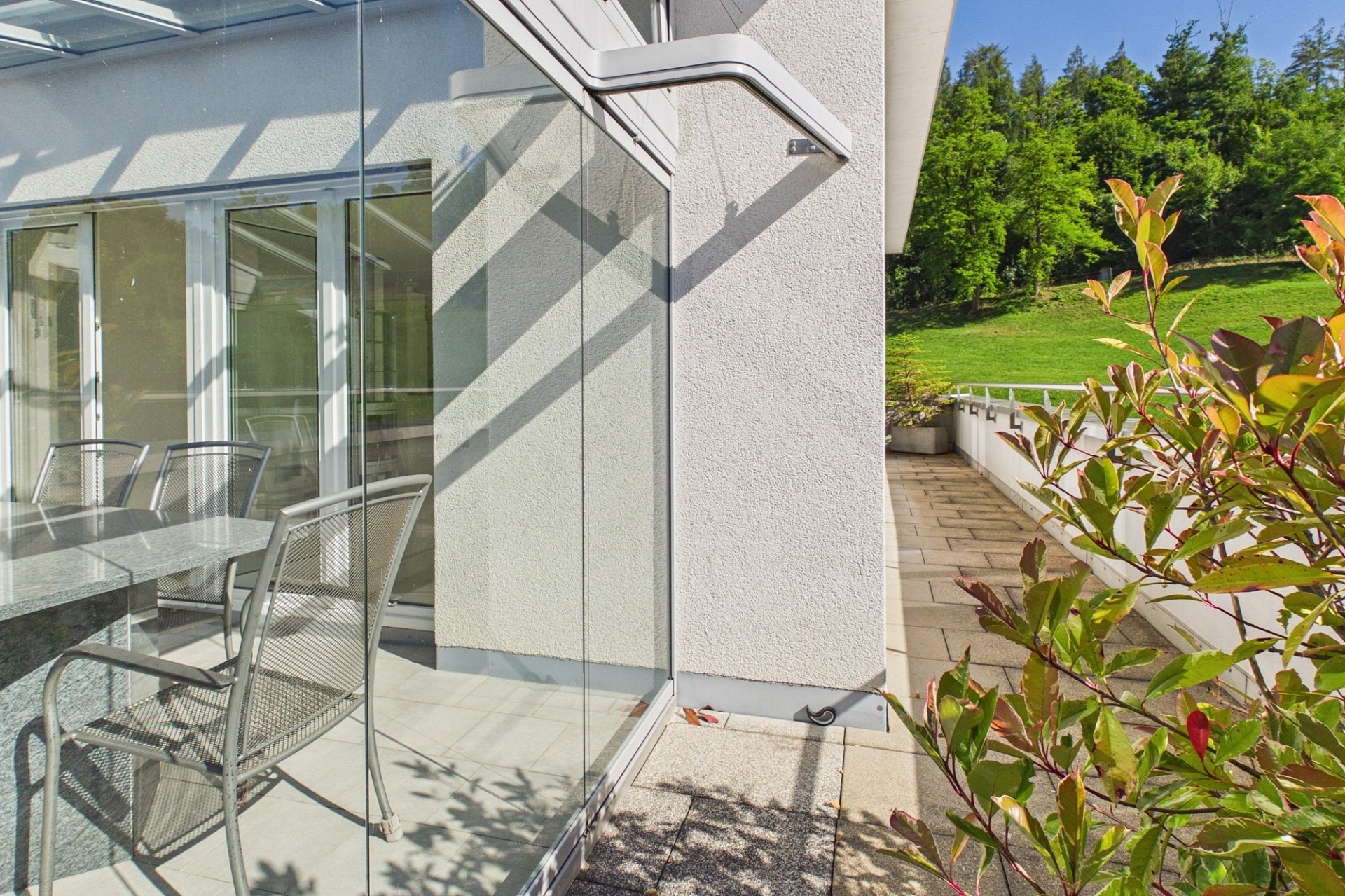Überdachte Terrasse mit Glasfront und Gartenblick