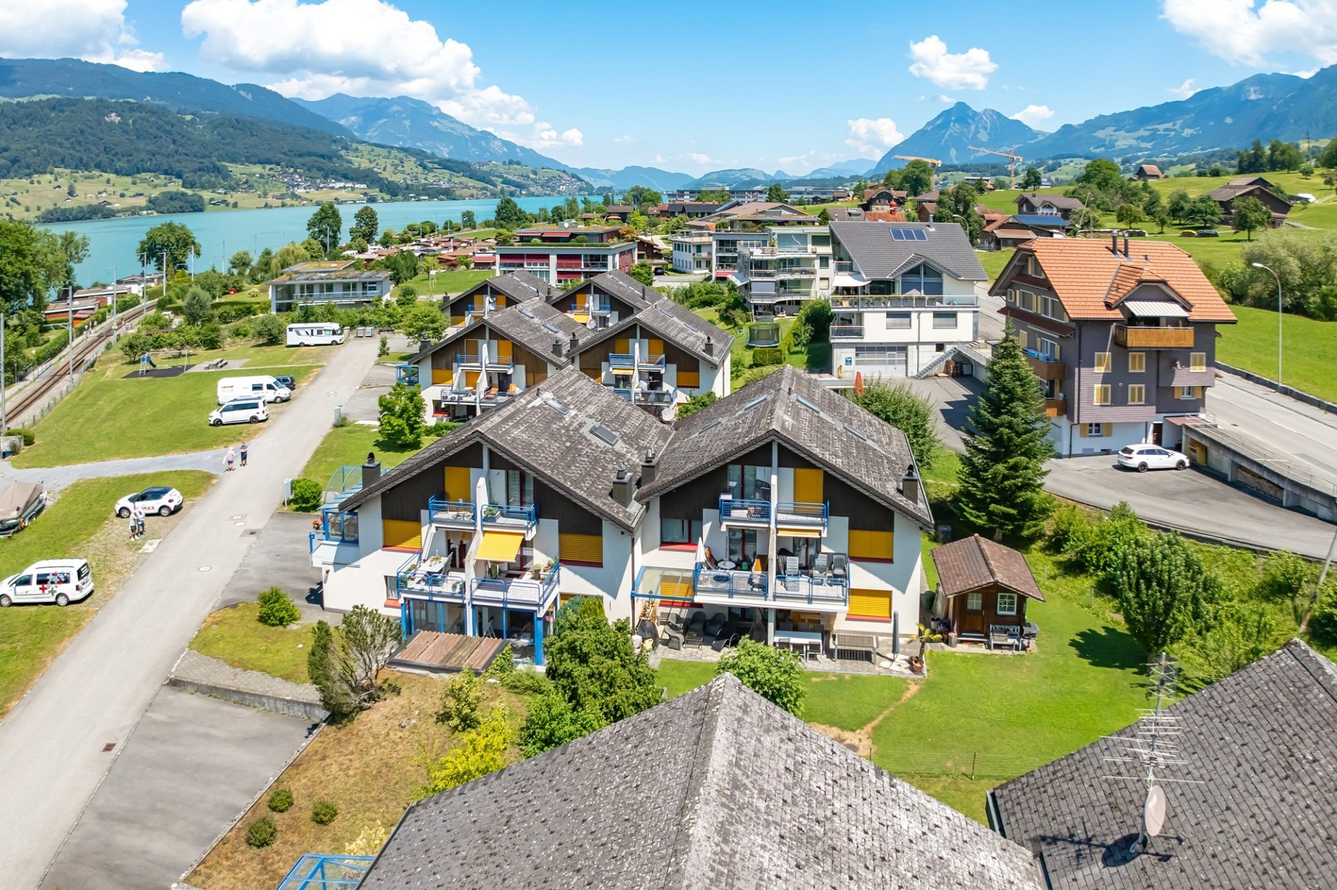 Luftaufnahme einer Wohnsiedlung am See mit Alpenpanorama