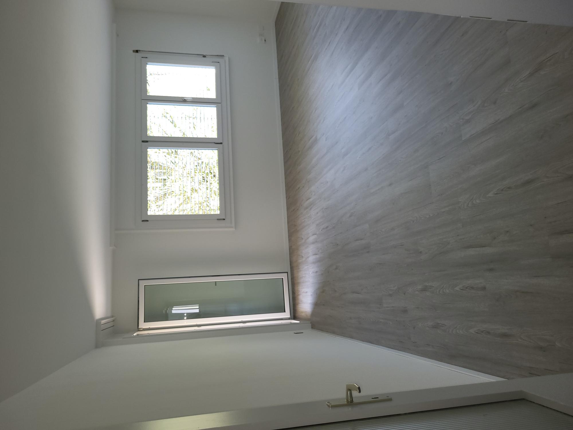 Leerer, heller Raum mit Fenster und Glastür