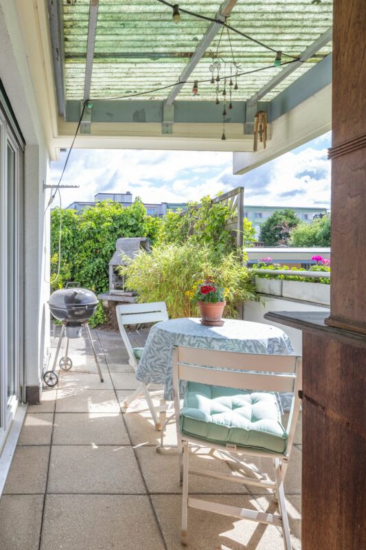 Sonniger Balkon mit Sitzgruppe und Grill