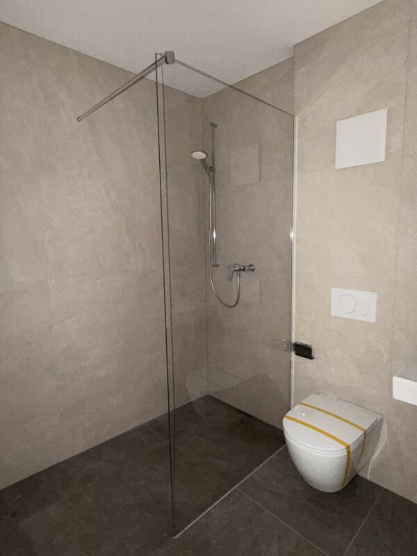 Modernes Badezimmer mit Glasduschabtrennung und wandhängendem WC