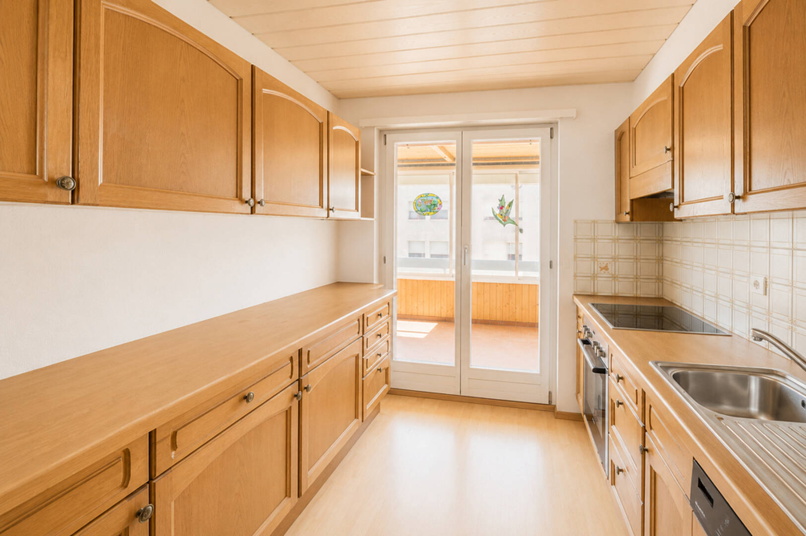 Helle Küche mit Holzfronten und Balkonzugang