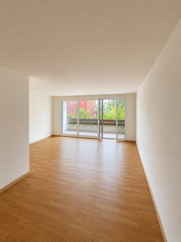 Leerer Wohnraum mit Balkon und Parkettboden