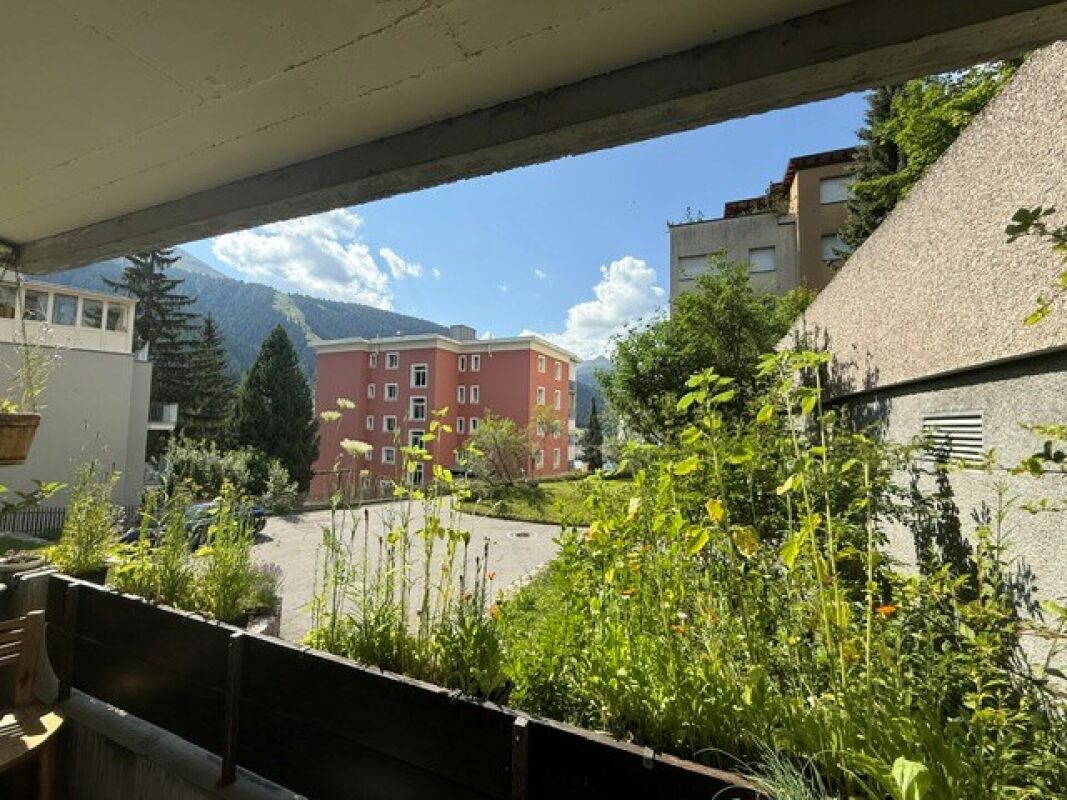 Blick vom Balkon in Richtung Wohngebäude und Berglandschaft