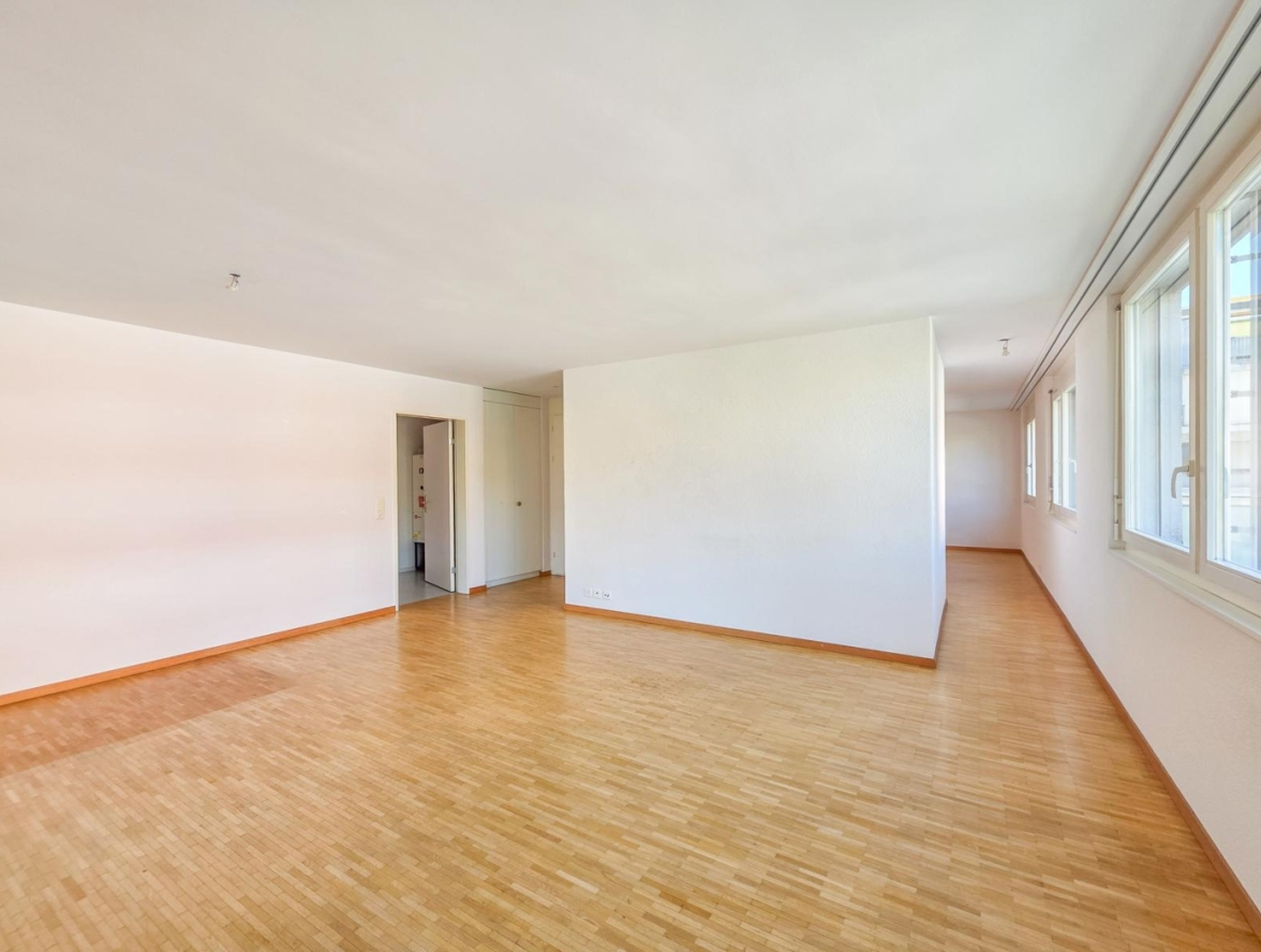 Leerer Wohnraum mit Parkett und Fenstern