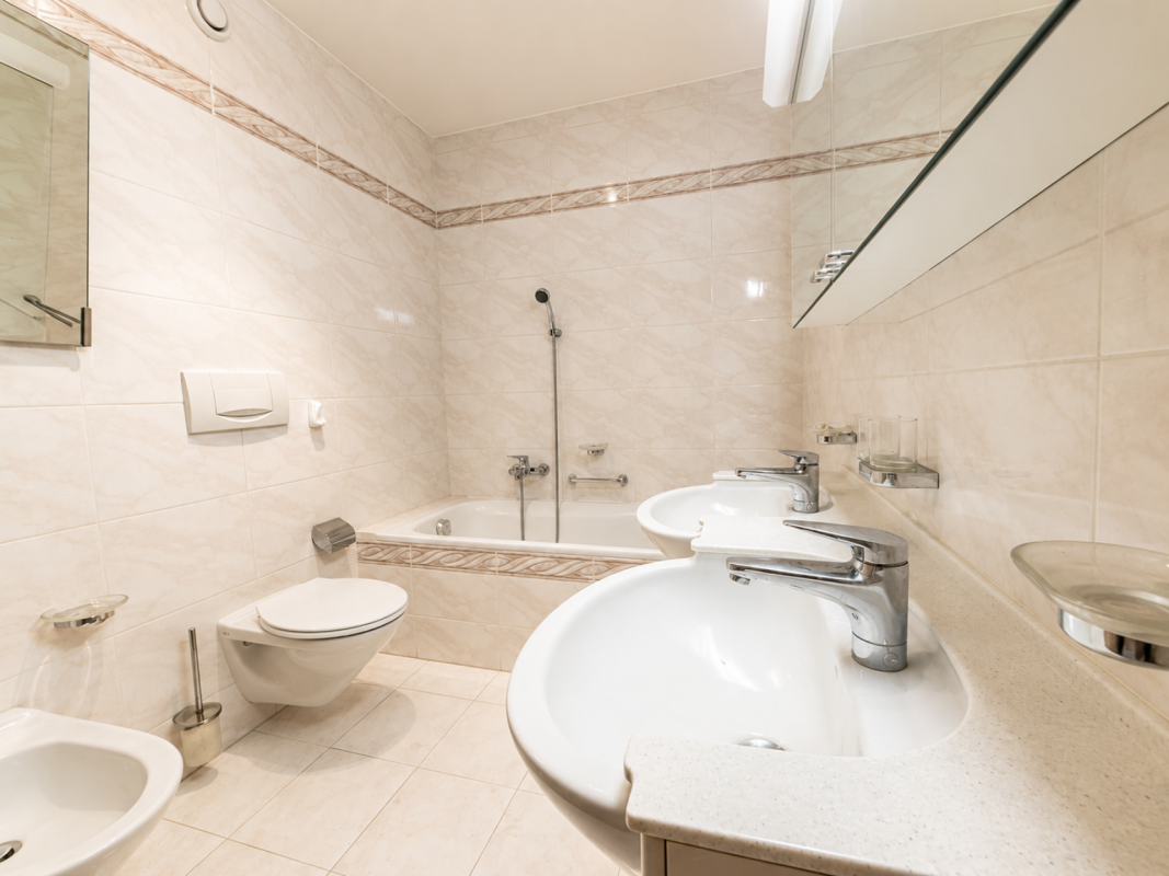 Helles Badezimmer mit Badewanne, Doppelwaschbecken und wandhängendem WC