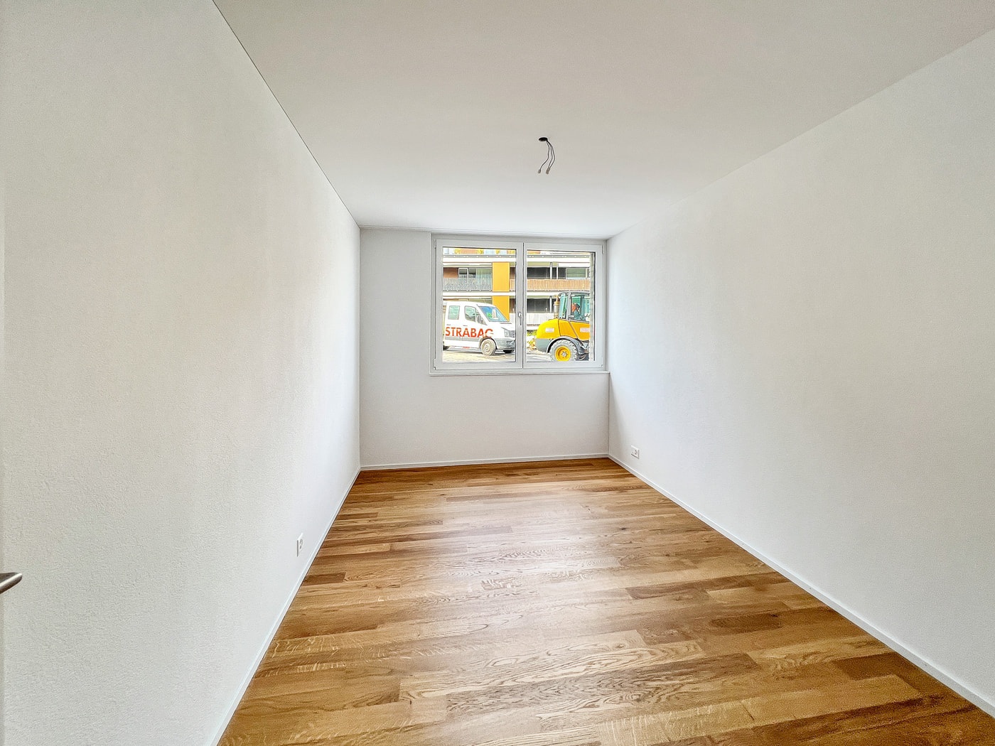 Leerer, neu wirkender Raum mit Holzfußboden und Fenster