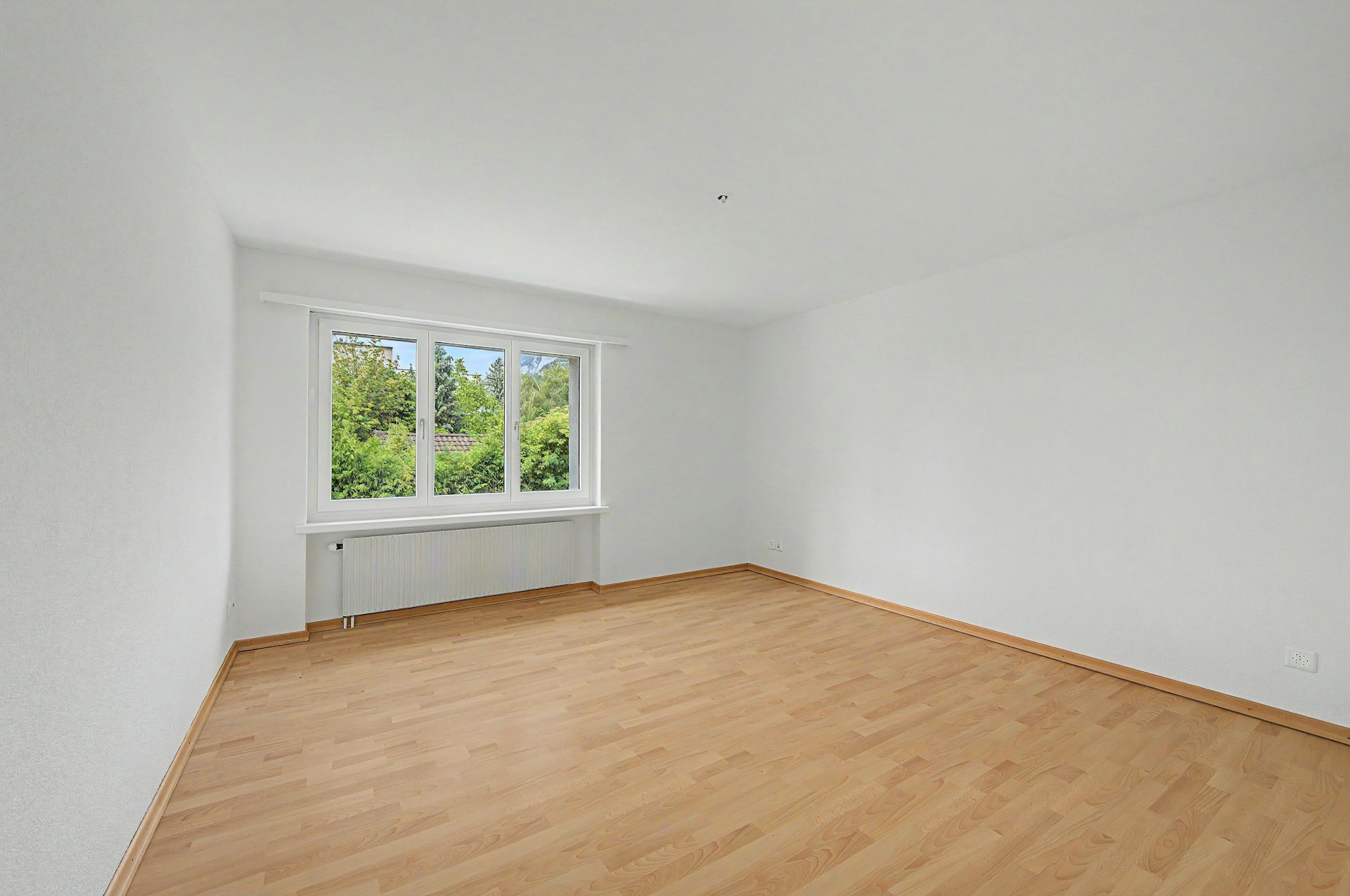 Leerer heller Raum mit Fenster und Parkettboden