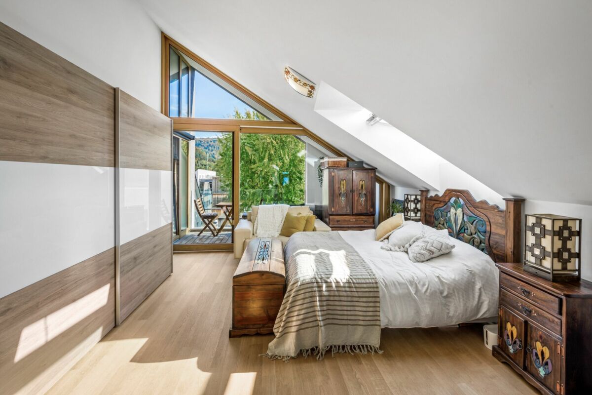 Helles Dachgeschoss-Schlafzimmer mit großem Fenster und Balkon