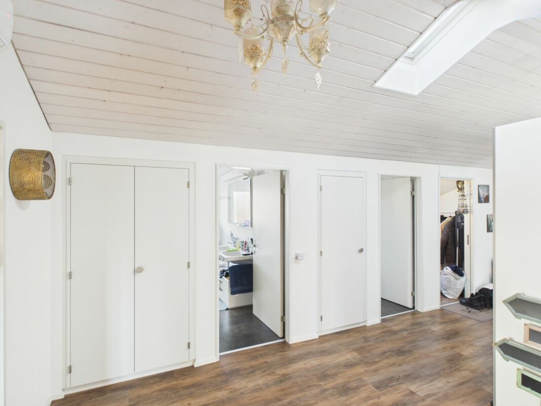 Helles Dachzimmer mit weißer Schrägdecke und mehreren Türen