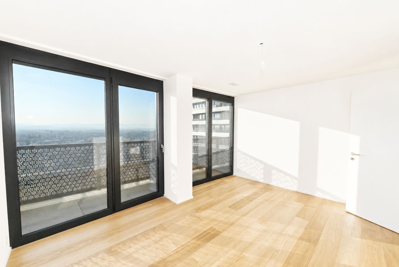 Heller leerer Wohnraum mit Balkon und Panoramablick