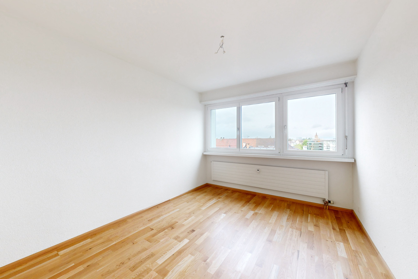 Leerer, heller Wohnraum mit Parkett und Fensterfront