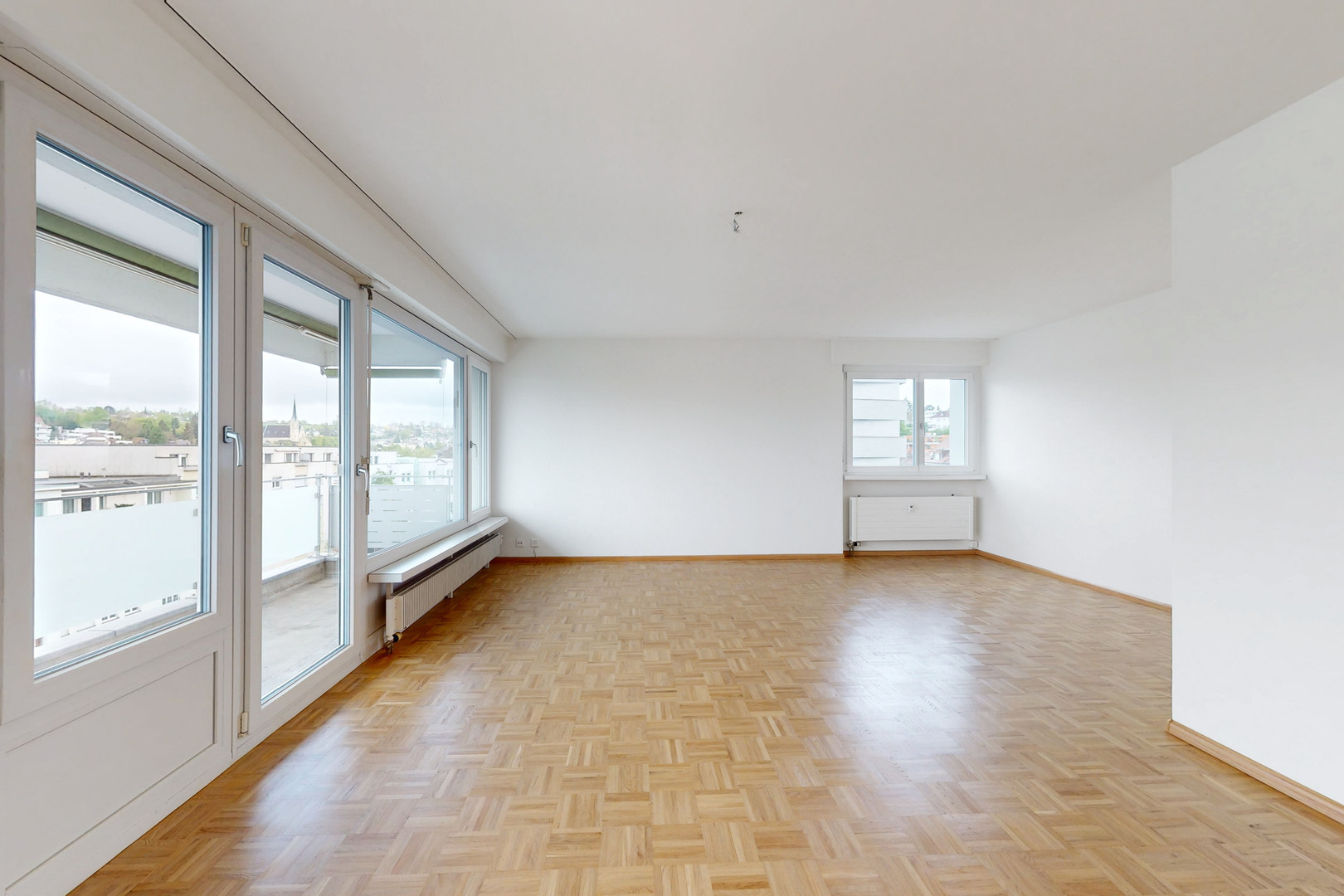Heller leerer Wohnraum mit Balkon und Parkettboden