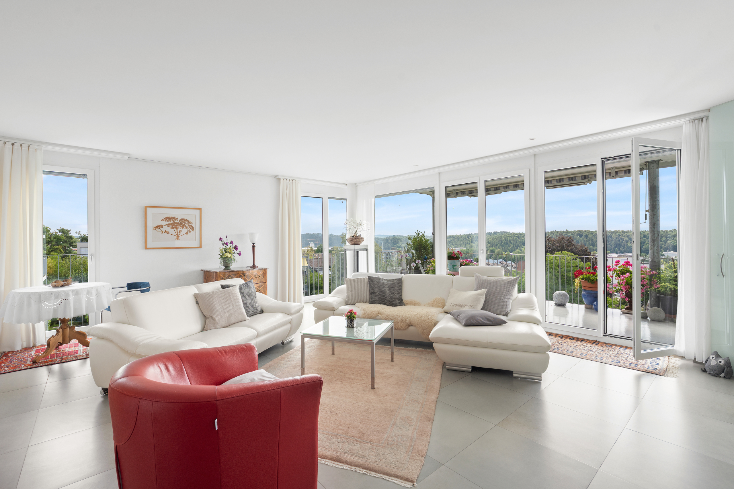 Helles, großzügiges Wohnzimmer mit Panoramafenstern und Balkonblick
