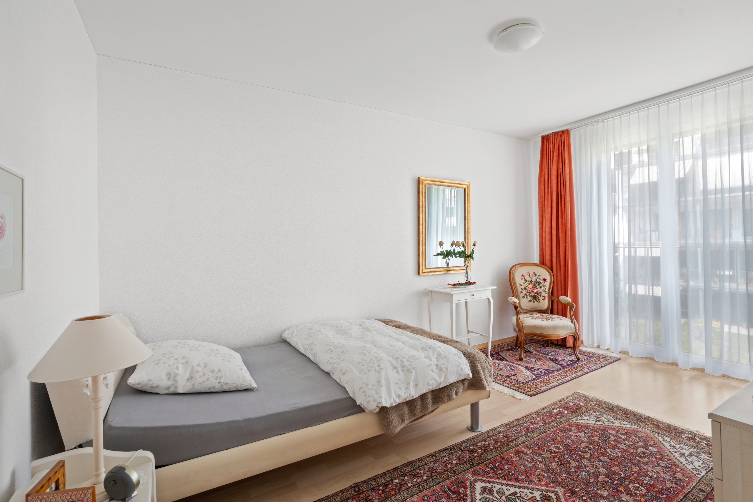 Helles Schlafzimmer mit Einzelbett und Balkonfenster
