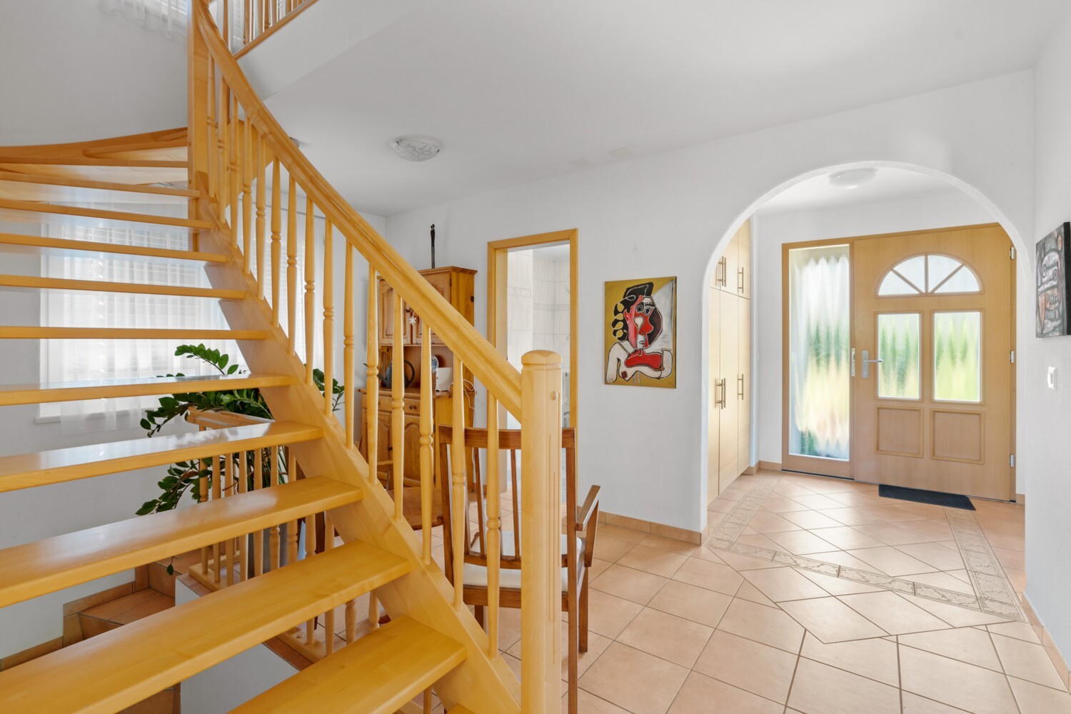 Heller Eingangsbereich mit offener Holztreppe