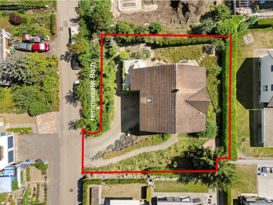 Luftaufnahme eines eingezäunten Einfamilienhauses mit Garten